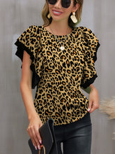 Model wearing an olive leopard print round neck blouse with flounce sleeves, paired with dark skinny jeans and simple accessories.