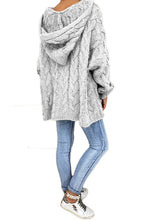 Model showcasing the back of a light gray color Tessyra Cable-Knit Hooded Sweater paired with jewelry, blue denim jeans, and white sneakers.