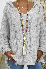Close-up photo of a model wearing the Light Gray color Tessyra Cable-Knit Hooded Sweater paired with jewelry and blue denim jeans.