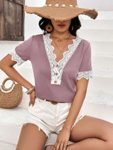 Lifestyle photo of model wearing a lilac Lace Detail V-Neck Short Sleeve T-Shirt at a weekend market, styled with white shorts and layered bracelets.