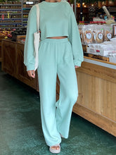 Woman standing in front of a counter in a store wearing the Aqua Waffle-Knit Round Neck Top and Pants Set
