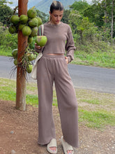 Woman standing next to a pole with a bunch of fruit on it wearing the Mocha Waffle-Knit Round Neck Top and Pants Set
