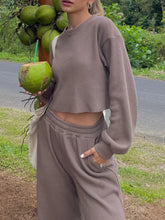 Woman standing next to a tree holding a coconut wearing the Mellara Mocha Waffle-Knit Round Neck Top and Pants Set