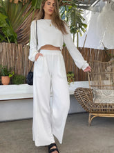 Model walking in Mellara rich white set styled with black shoulder bag and black slides.