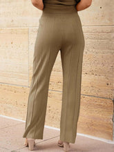 Close-up back view of wide leg pleated knit pants on model wearing Mirajella Luxe camel set