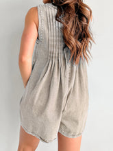 Pleated mocha romper shown from behind, styled with minimalist clutch and pointed flats.