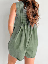 Model in moss romper showing back pleats and natural drape—earthy chic with a high bun and leather sling bag.