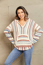 Front view of a woman in the Ollavon Striped Hoodie with playful stripes, an adjustable hood, and roomy kangaroo pocket.