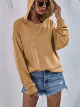 a model wearing a mustard color Zephyra Breeze Dropped Shoulder Hoodie paired with tinted glasses, jewelry, and light blue denim shorts.