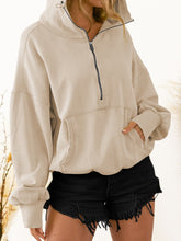 A model wearing the beige color Nuvella Zip-Up Dropped Shoulder Hoodie paired with distressed tan denim shorts.