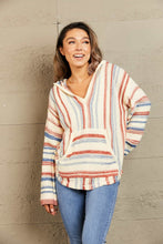 Side profile of a woman wearing the Ollavon Striped Hoodie, highlighting the relaxed silhouette, adjustable drawstring hood, and vibrant multicolor striped pattern.