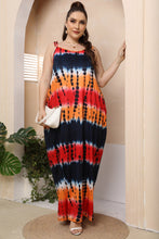 Woman relaxing at a resort beach house wearing Ombravelle Tie-dye Maxi Dress with accessories for a casual styled look.