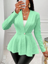 A woman taking a selfie photo at a restaurant wearing the neon green One Button Textured Peplum Cardigan paired with black leather pants, jewelry, and heels.