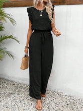 Model waking on a beach resort wearing the Black Papiloniya™ Lace Trim Round Neck Top and Pants paired with accessories for a casual complete look.