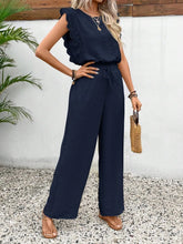 Model wearing the Papiloniya™ Lace Trim Round Neck Top and Pants Set in dark blue. Featuring lace trim top and wide-leg pants, styled with sandals.