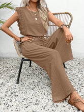 Woman sitting outside under a palm tree in a Taupe Papiloniya™ Lace Trim Top and Pants Set, styled with pearls and strappy wedged heels.