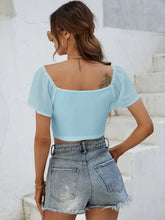 Back view of Glowflutter Crop Top showing soft fabric and flutter sleeve flow, worn by model in pastel blue.