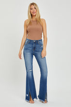 Model styling RISEN front slit jeans with boots and a tucked blouse