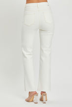 A female posing from the back wearing cream RISEN Full Size High Rise Tummy Control Straight Jeans paired with a cream off-shoulder blouse, jewelry, and clear round open-toe heels.