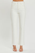 A female posing from the front wearing cream RISEN Full Size High Rise Tummy Control Straight Jeans paired with a cream off-shoulder blouse, jewelry, and clear round open-toe heels.