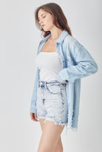 Model mid-stride in RISEN Raw Hem Denim Shorts paired with a fitted bodysuit and ankle boots, ideal for concert nights and festivals.