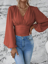 Front view of the Rust Balloonique™ Blouse highlighting smocked neckline and balloon sleeves, paired with light blue washed jeans, and jewelry.