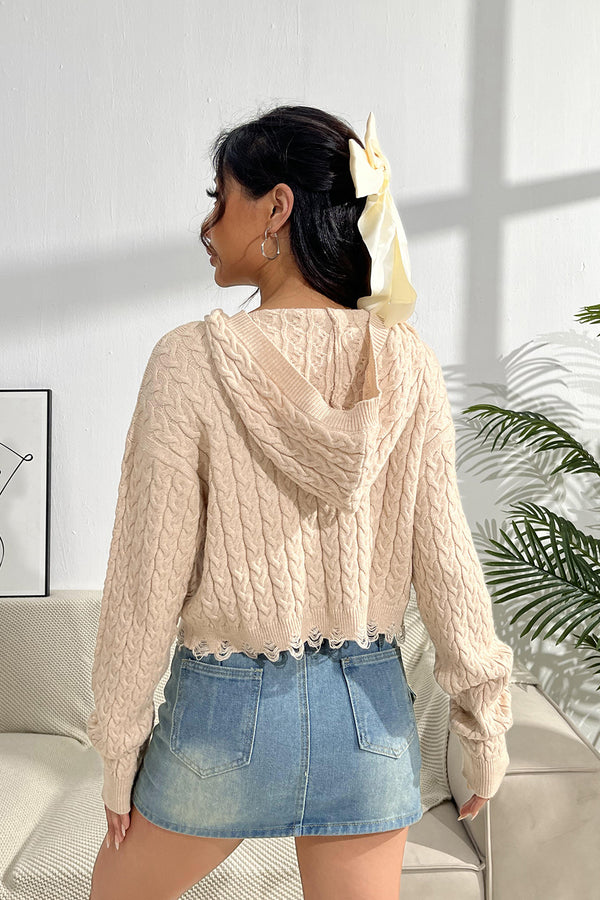 a model showcasing the back of a sand color Urban Cable Knit Sweater paired with jewelry and a light blue denim skirt.