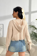 a model showcasing the back of a sand color Urban Cable Knit Sweater paired with jewelry and a light blue denim skirt.