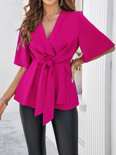 Side profile of model wearing the hot pink tied front peplum blouse, highlighting the flattering waist-cinching tie and feminine silhouette.