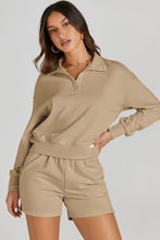 Model poses while wearing a tan Half-Button Sweatshirt and Shorts Active Set.