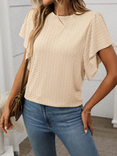 Model in a tan Round Neck Flutter Sleeve T-Shirt, styled with wide-leg linen pants and a straw tote at a sunny garden brunch.