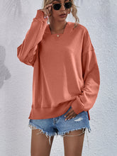 a model wearing a tangerine Zephyra Breeze Dropped Shoulder Hoodie paired with tinted glasses, jewelry, and light blue denim shorts.