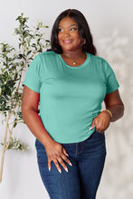 Model smiling in vibrant teal solid short sleeve t-shirt