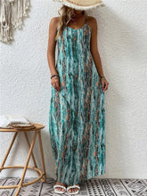 Model posing in the Turquoise color Jewel of Northern Lights Maxi Cami Dress paired with a woven straw hat with white raw trim, jewelry, and white heels.