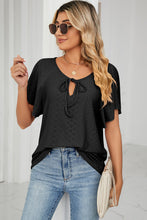 Woman wearing a black Veluretta Mistflair Blouse shopping at a grocery market in the city.