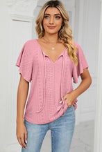 Woman in a carnation pink Veluretta Mistflair Blouse sipping coffee at a city café.