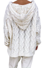 Model showcasing the back of a white color Tessyra Cable-Knit Hooded Sweater paired with jewelry, and white slacks.
