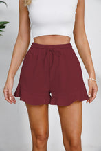 Model wearing wine Plus Size Drawstring Ruffle Hem Shorts, with chic deep hue and tie waist.