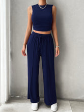 Zenvara Loungewear Set in dark blue styled with white sneakers and accessories, wall pose