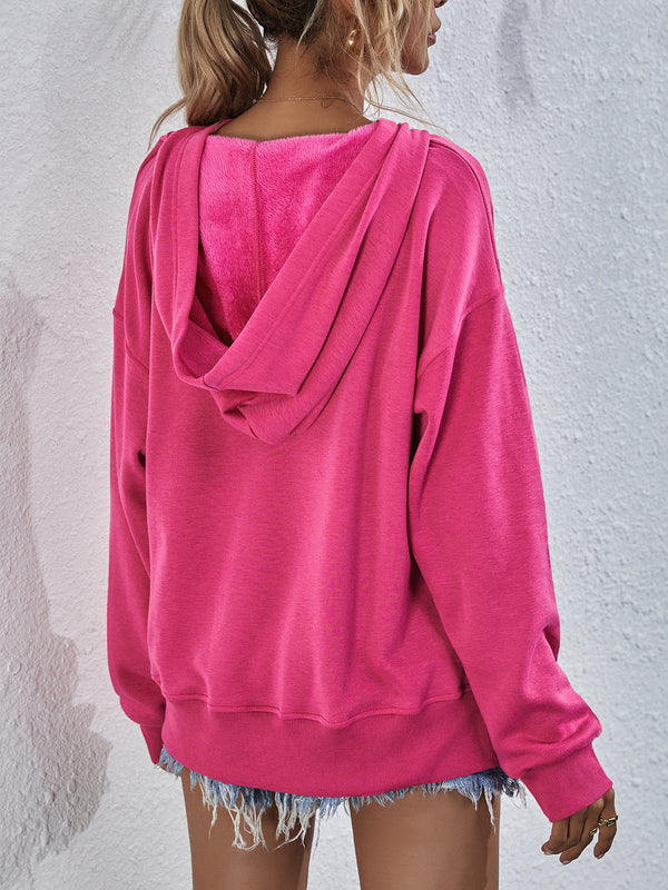 Woman showcasing the back of a pink Zephyra Breeze Dropped Shoulder Hoodie paired with light blue denim shorts.
