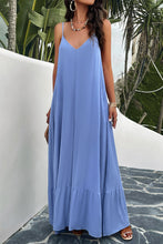 a model posing on a balcony wearing a sky blue Backless Maxi Cami Dress with Pockets  paired with jewelry, a woven handbag, and clear heels