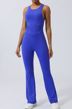 Model in Blue AerisCross Vivanta Jumpsuit, front view showcasing crisscross straps and sleek silhouette.