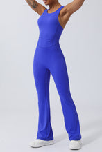 Side view of model stretching arm overhead in Blue AerisCross Vivanta Jumpsuit.