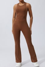 Model in Brown AerisCross Vivanta Jumpsuit, front view showcasing crisscross straps and sleek silhouette.