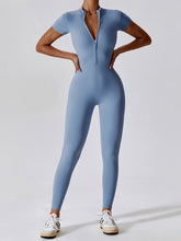Model in Light Blue FlowFit Jumpsuit, front view showing half‑zip and slim fit.