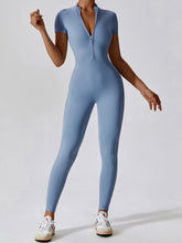 Model relaxing in Light Blue FlowFit Jumpsuit on sofa with cozy sneakers.