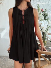 Model wearing black Allurista™ mini dress at an evening rooftop event with clutch in hand.