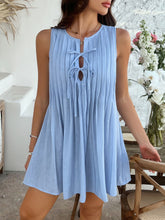 Model wearing light blue Allurista™ mini dress strolling through a blooming courtyard.