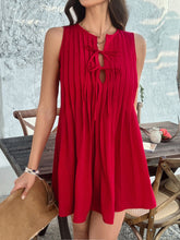 Model in scarlet Allurista™ mini dress laughing with friends at a sunset garden party surrounded by hanging lanterns.