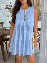 Model in light blue Allurista™ mini dress enjoying a daytime outdoor wedding by a floral arch.